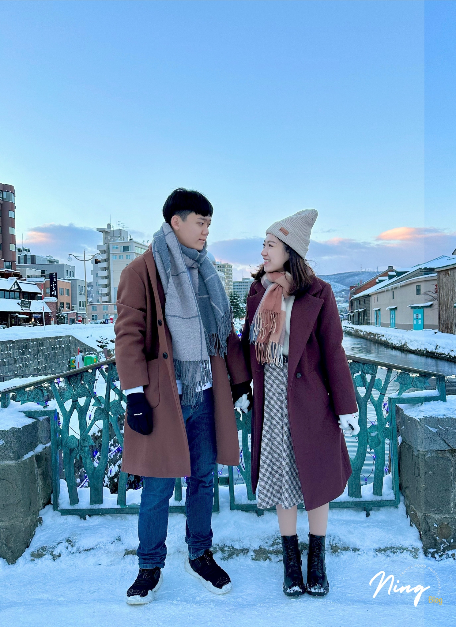 a couple standing on a snowy bridge at Otaru Canal during winter