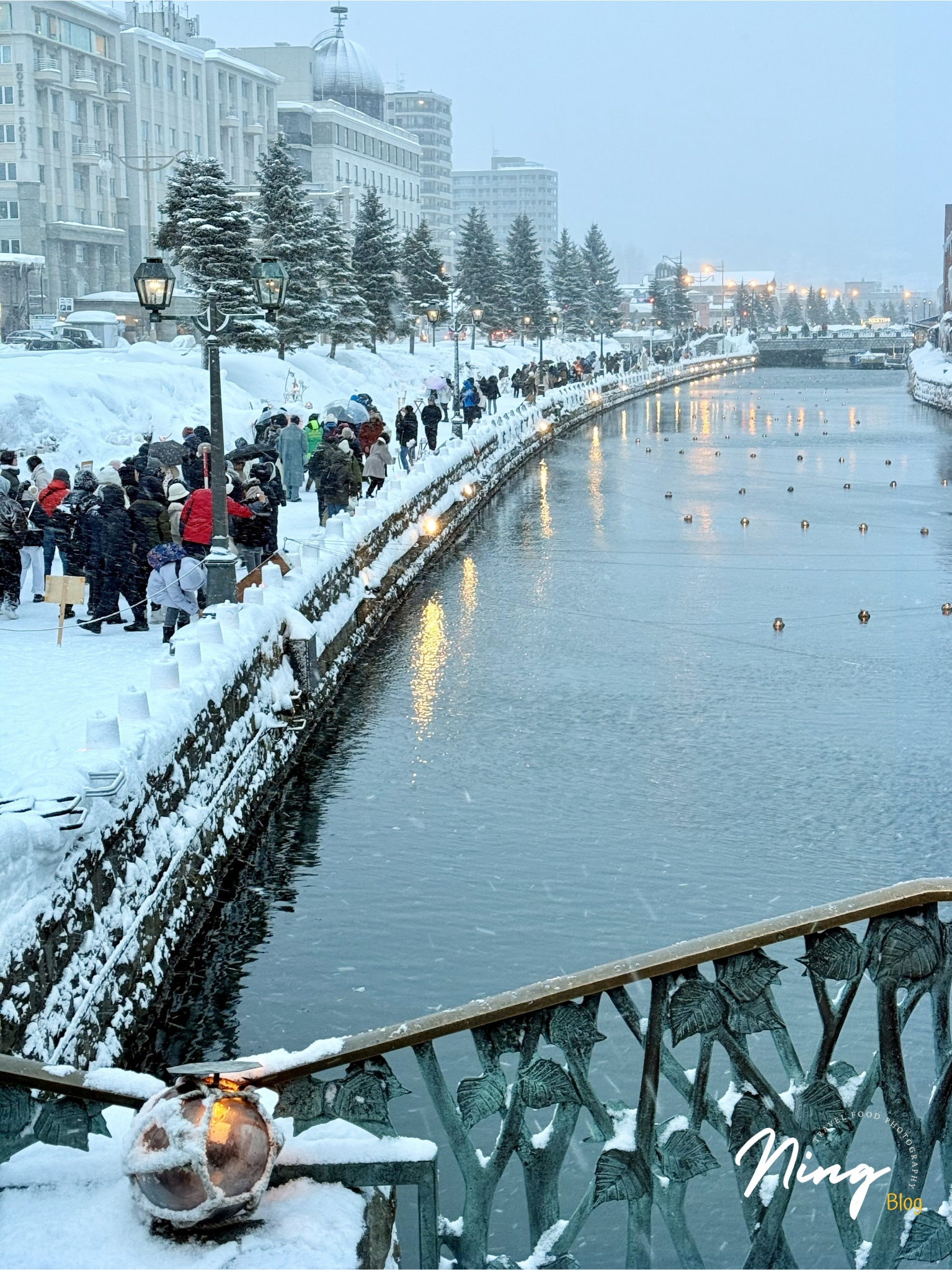 Winter snowy view of Otaru Canal with crowds gathering along the river.
