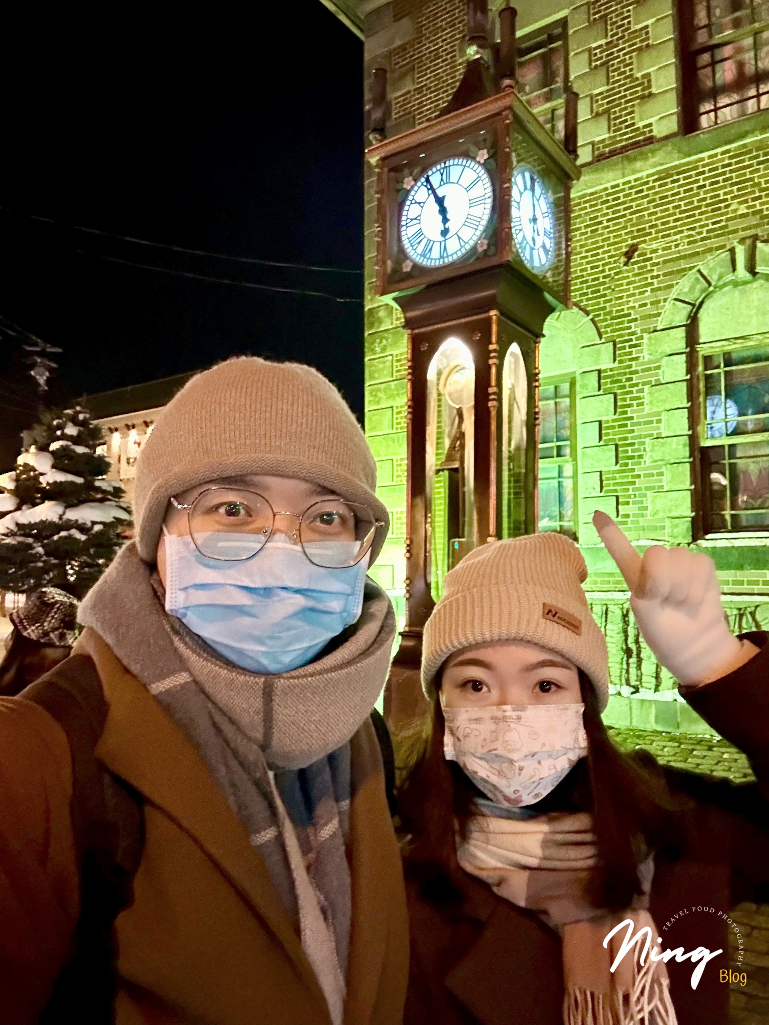 小樽蒸汽鐘前的夜間合照，旅人指向亮燈的時鐘