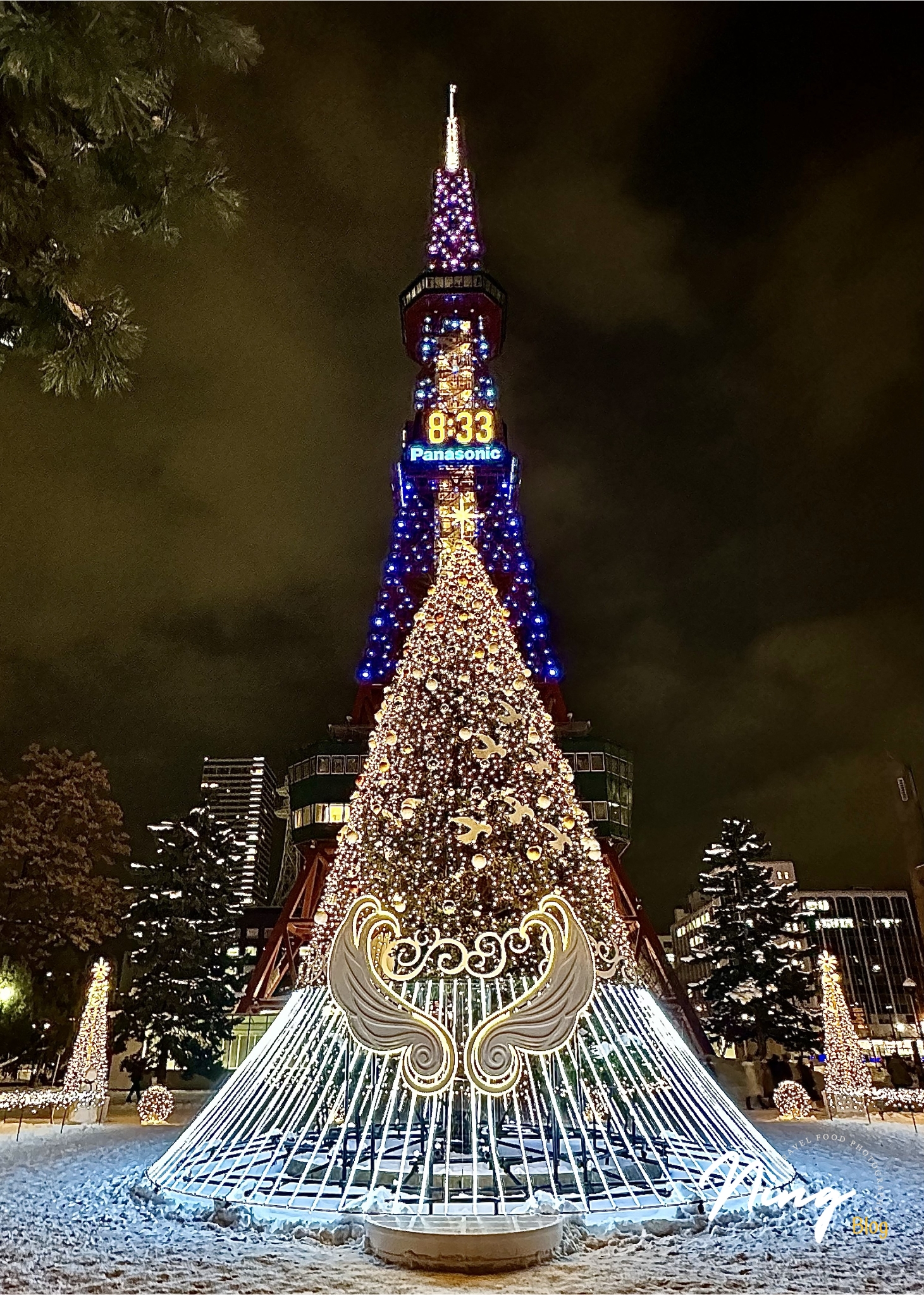 北海道札幌大通公園，札幌電視塔的冬季夜間點燈，塔身與聖誕樹裝飾著五彩燈光與翅膀造型。